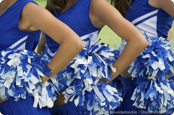 Midsection of young female cheerleaders holding pom-poms