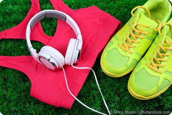 Sport clothes, shoes and headphones on green grass background