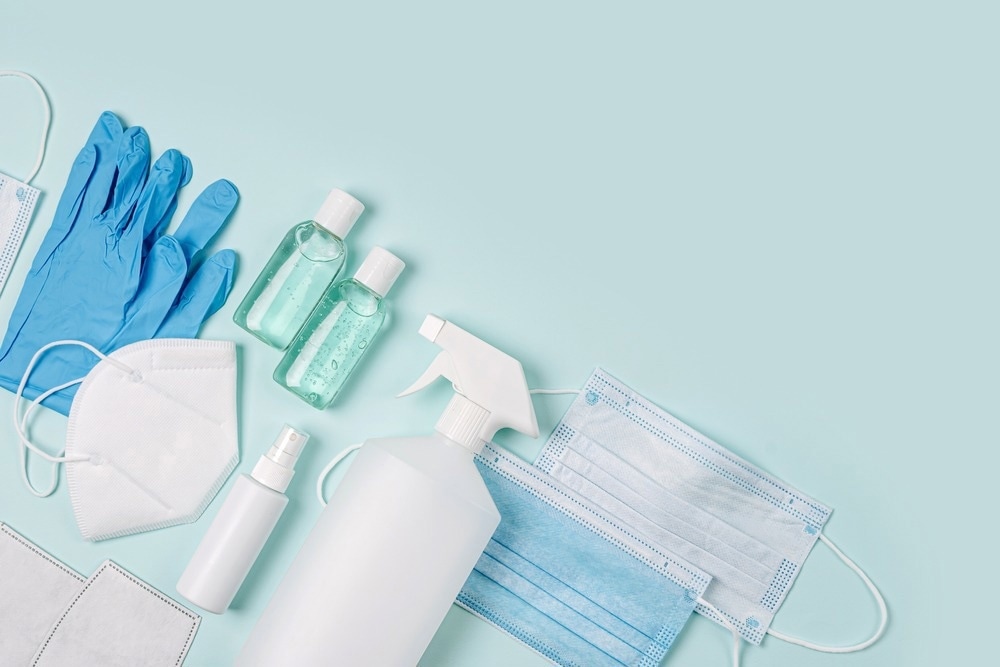White medical masks and respirators with glove, hand sanitizer on blue background. Image Credit: Igisheva Maria/Shutterstock.com
