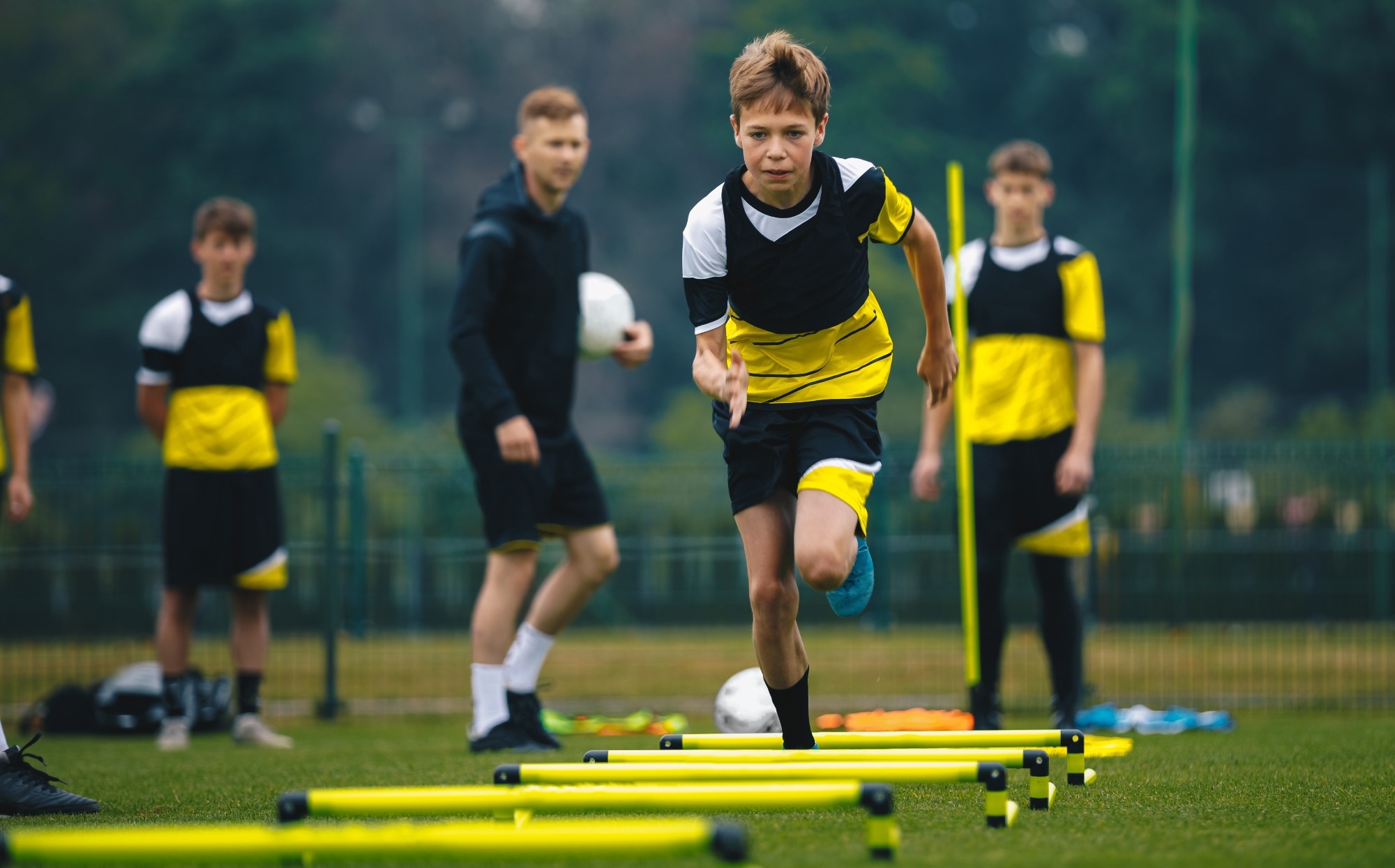 Junior level soccer player running and doing skipping exercise with hurdles during practice session
