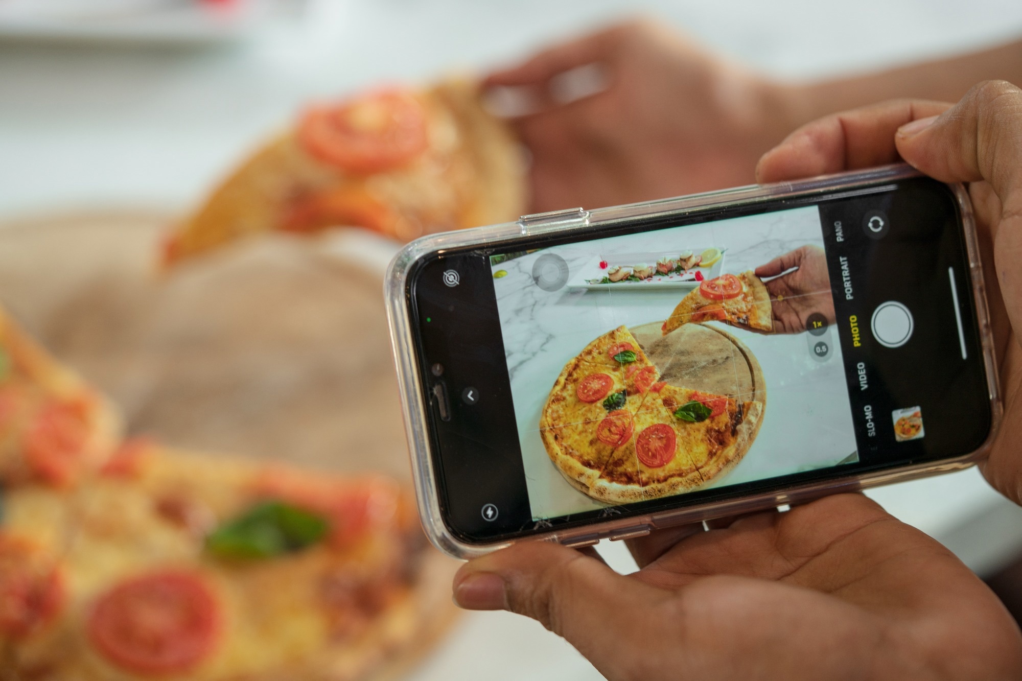 Person taking photo of pizza with smartphone