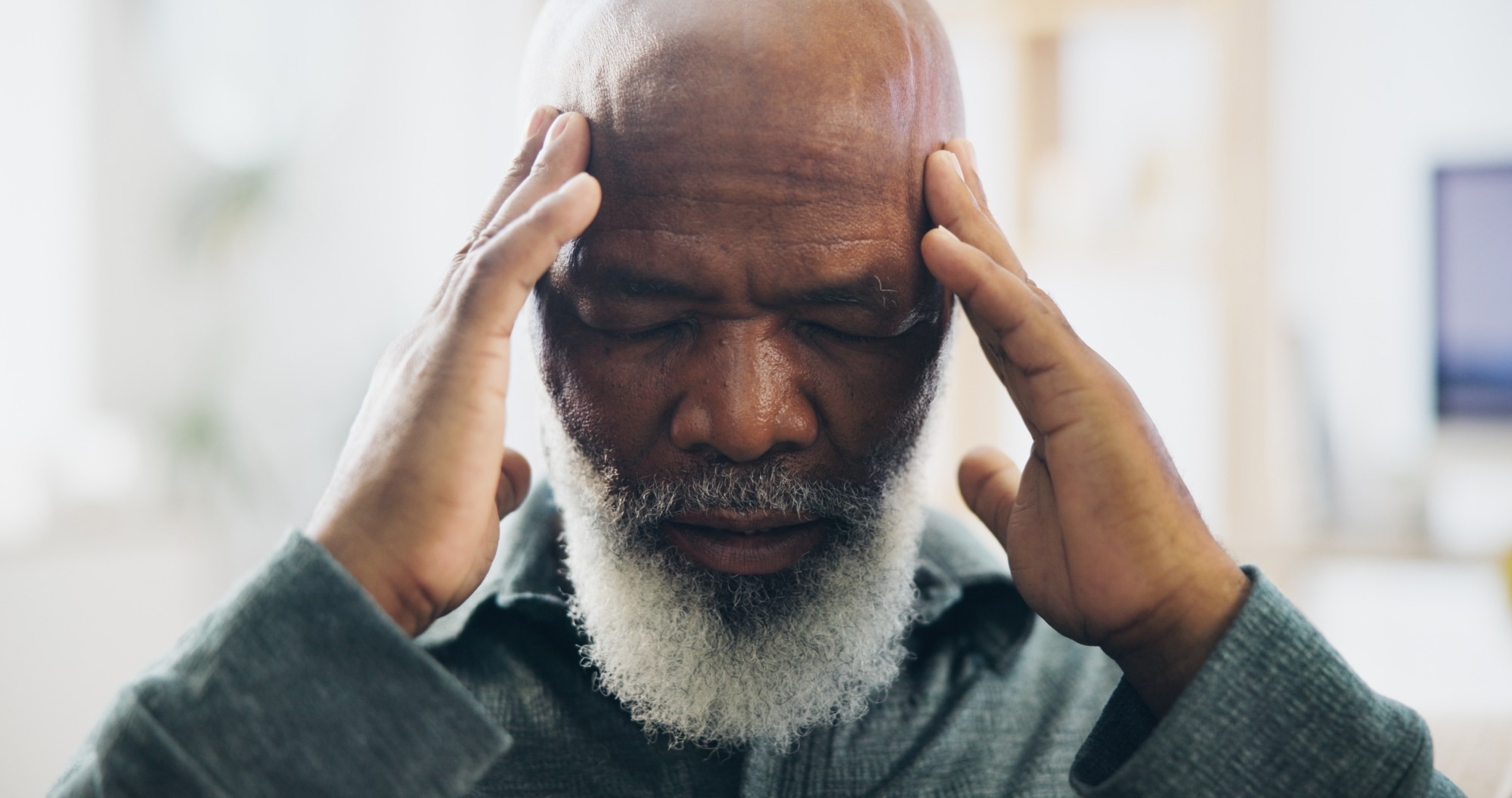 Older age man with hands placed on temples
