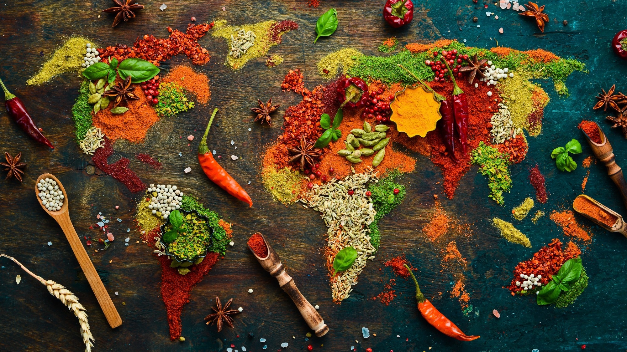 World map: Pepper, salt, paprika, basil, turmeric. On a black wooden board.