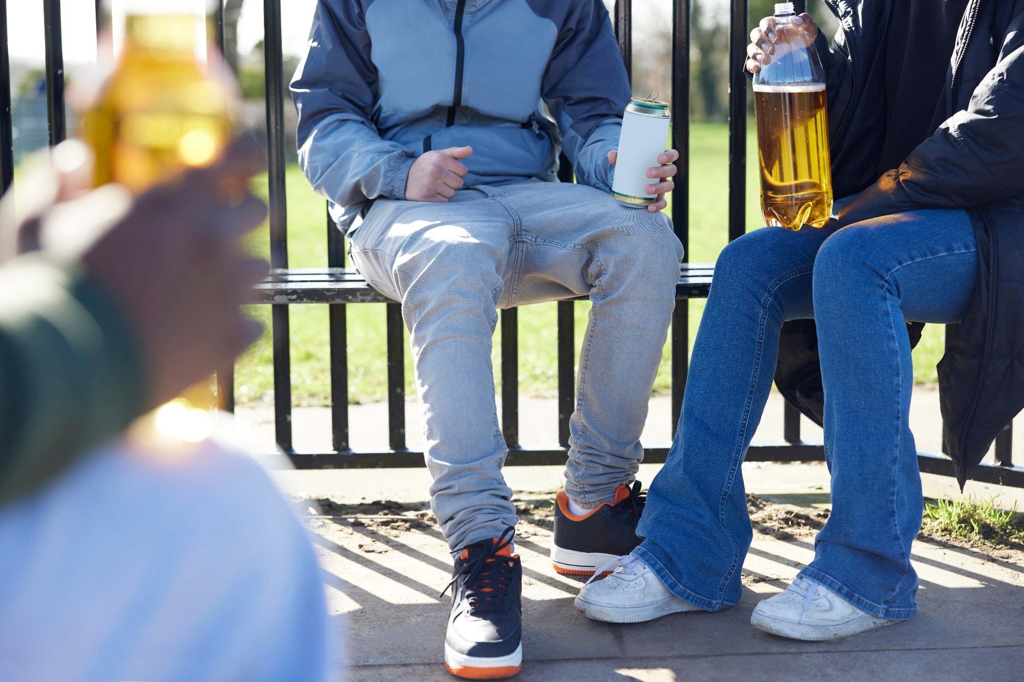 Close Up Of Underage Teenagers Drinking Alcohol In Park