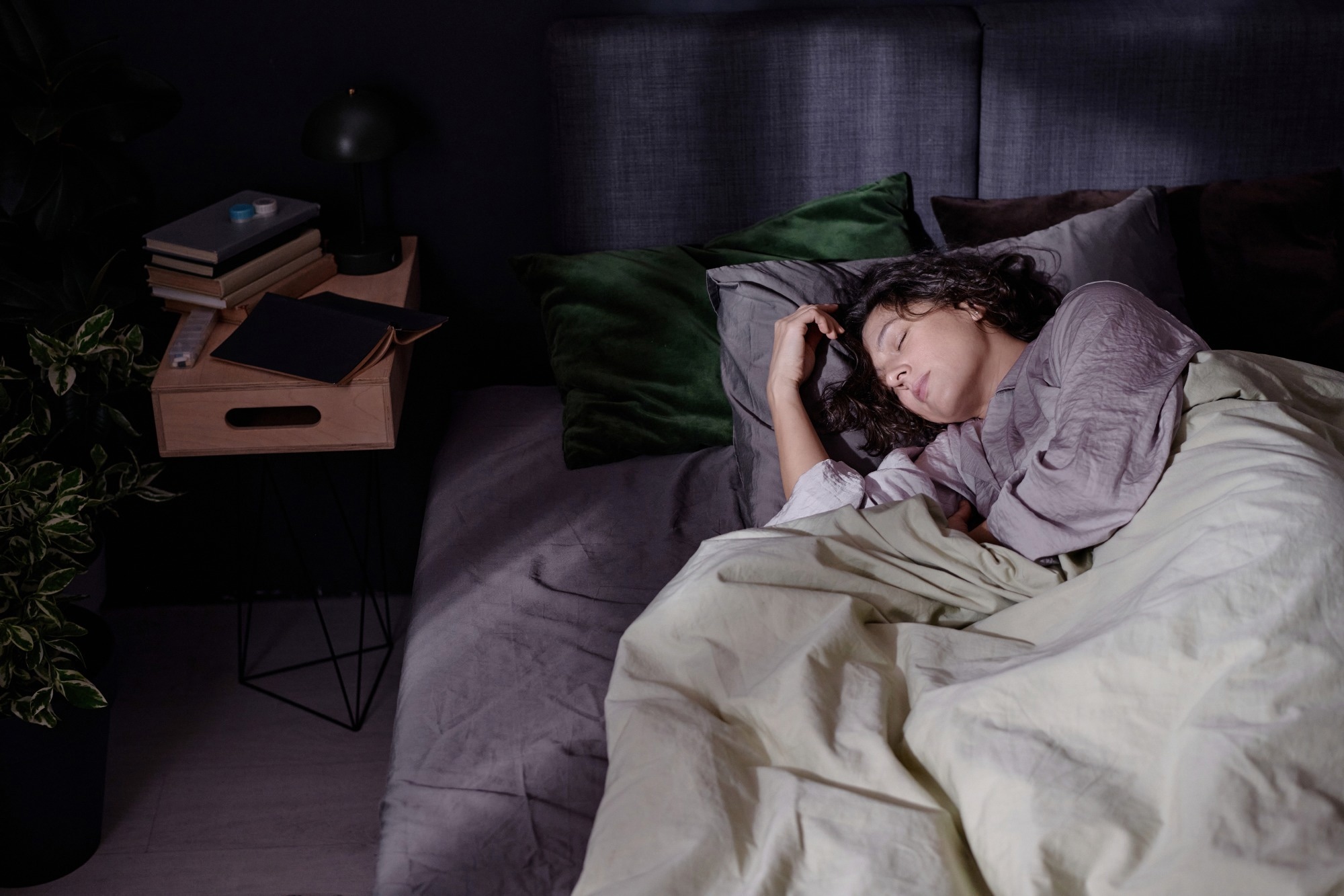 High angle shot of tired brunette woman sleeping in bed while sun illuminating room through window