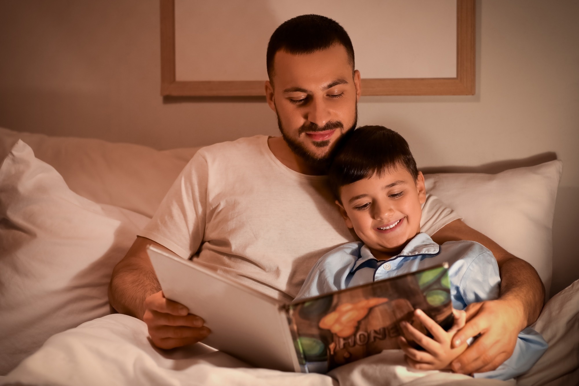 Father and his little son reading bedtime story in bed at home